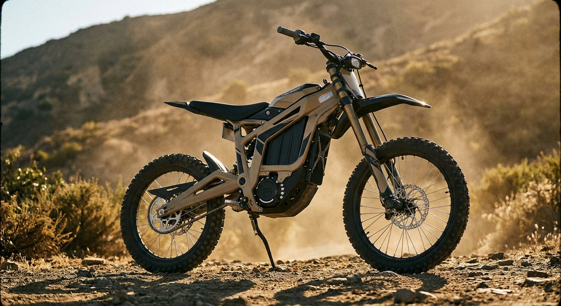 A modified Talaria electric dirt bike parked on rugged off-road terrain in golden afternoon light, showcasing aftermarket upgrades and aggressive tires.